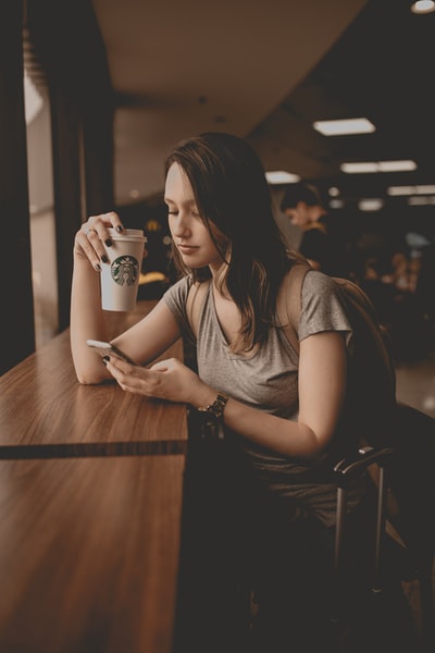 女人拿着星巴克一次性杯子和智能手机
